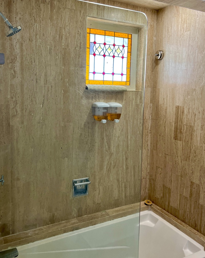 a bathroom with a stained glass window and soap dispensers