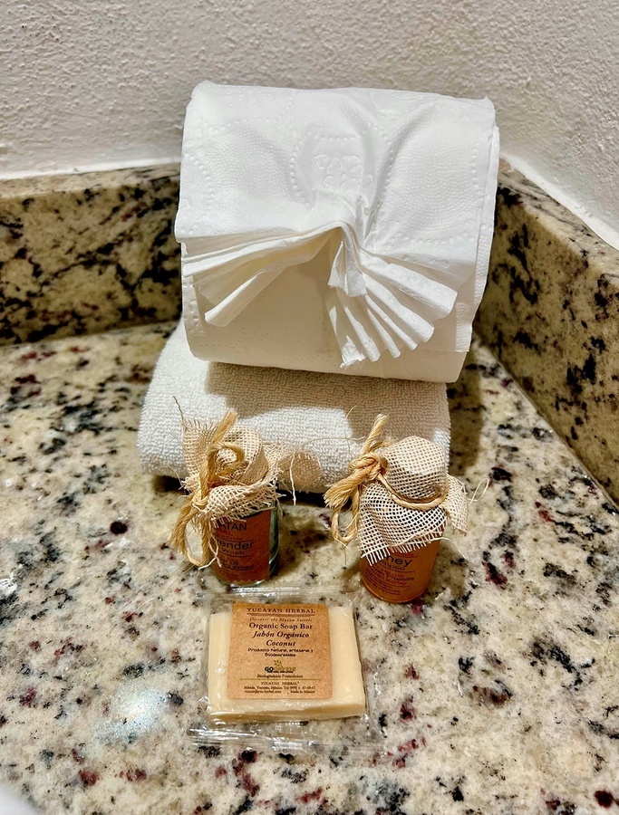 a bathroom counter with a towel a soap and a jar of honey