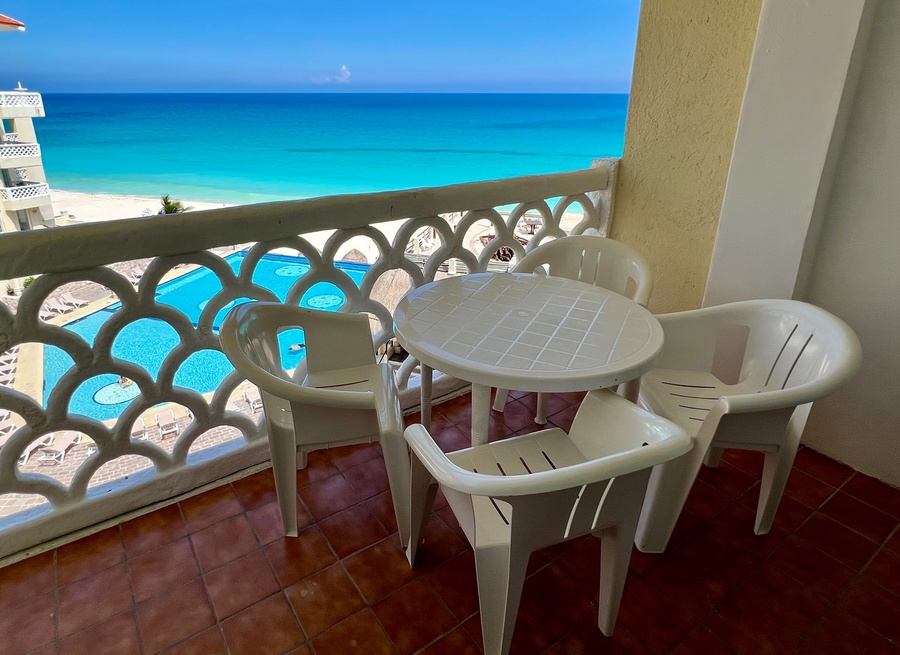 una mesa y sillas en un balcón con vistas al océano