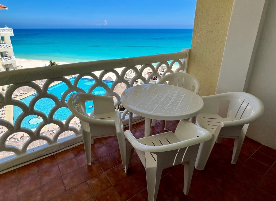 a table and chairs on a balcony overlooking the ocean