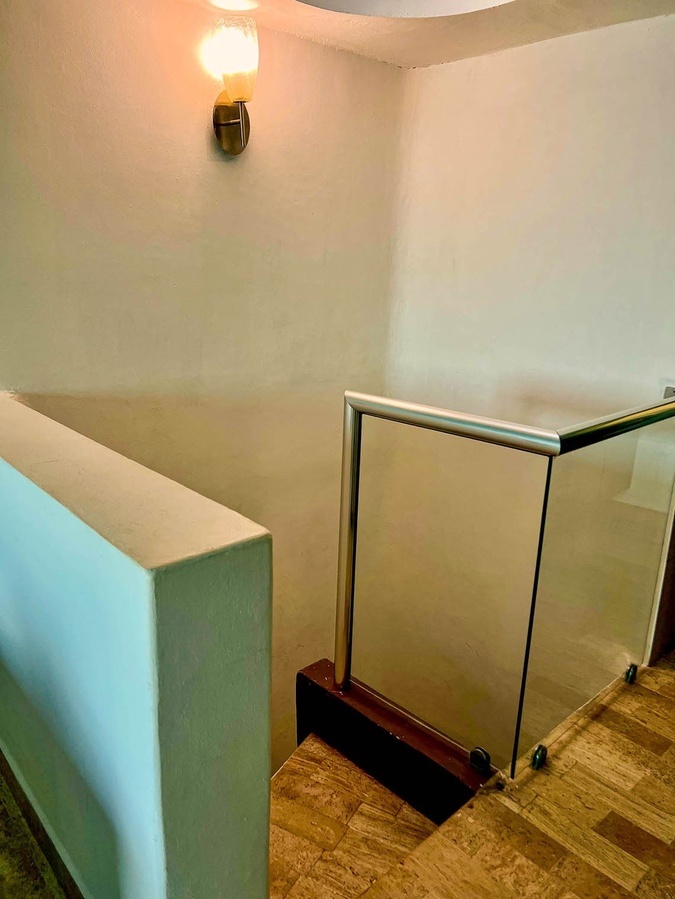 a staircase with a glass railing and a light on the wall