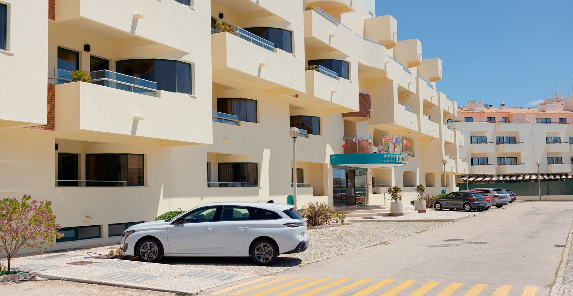 un coche blanco está estacionado frente a un edificio de apartamentos