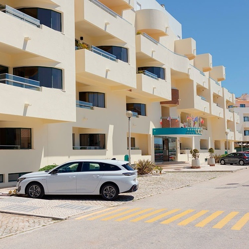 un coche blanco está estacionado frente a un edificio de apartamentos