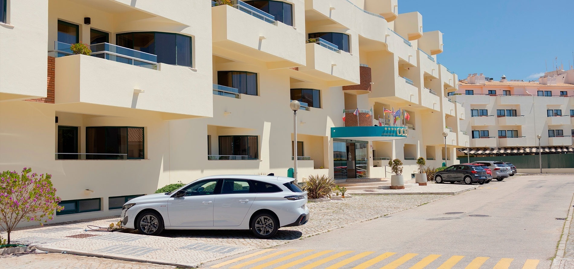 un coche blanco está estacionado frente a un hotel