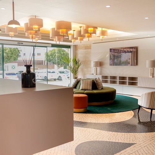 un área de recepción de un hotel con un sofá y sillas