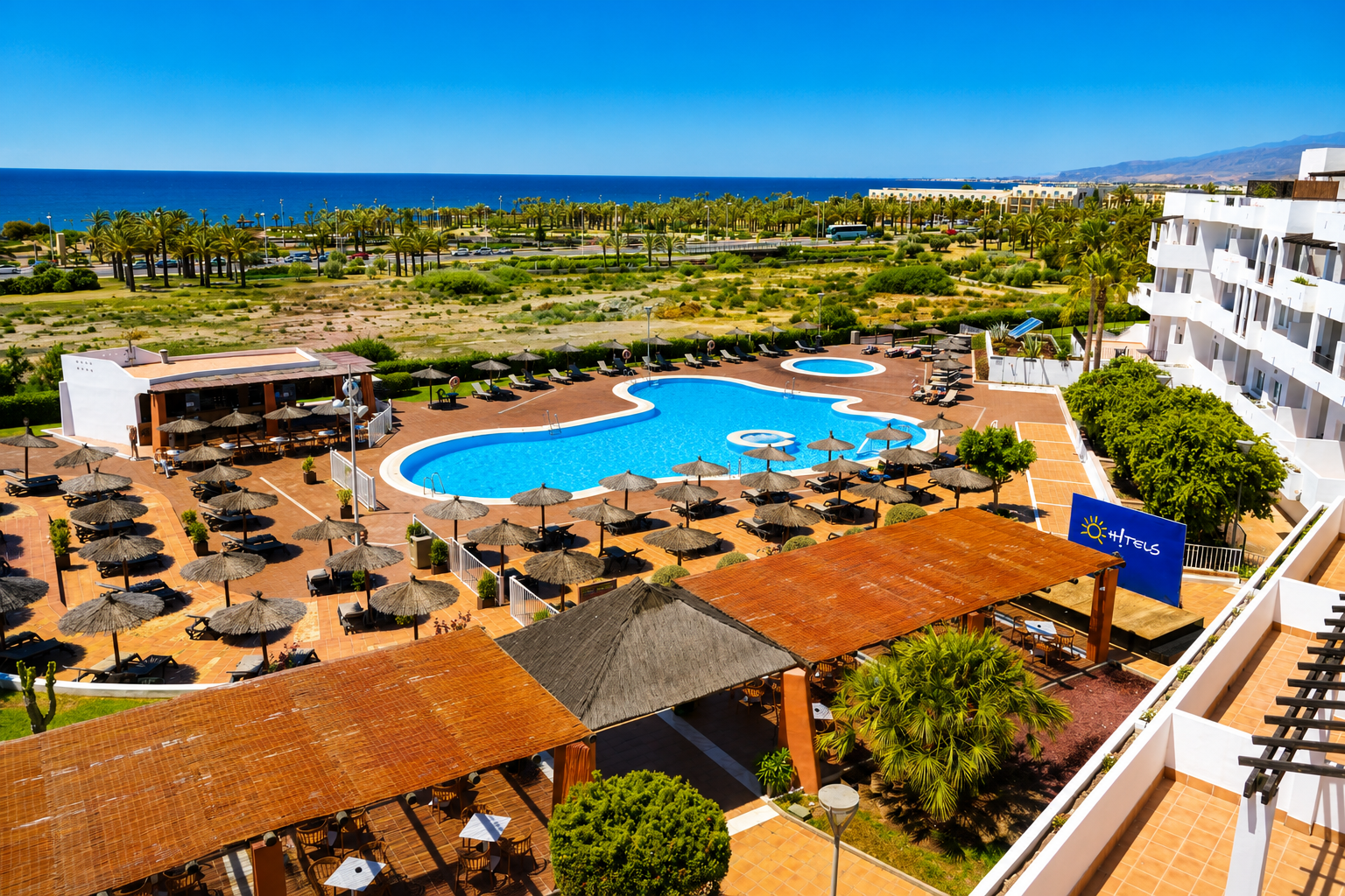 Ohtels: Corporativa - Relaxing pool area at Ohtels hotel with sun loungers and umbrellas.