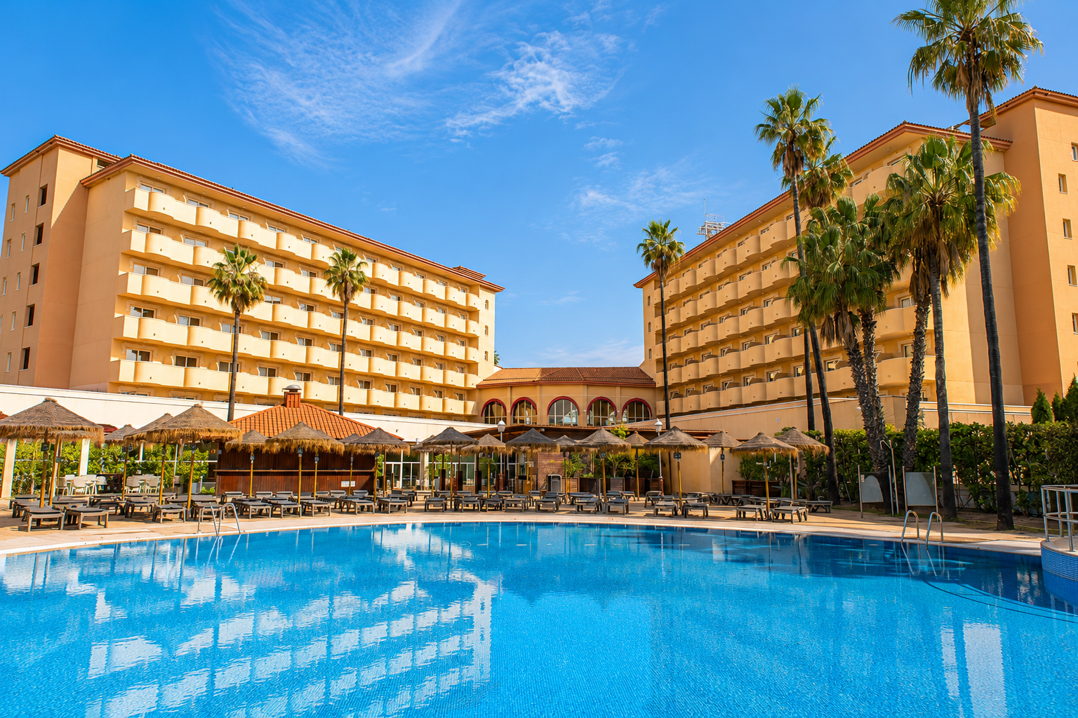 Piscina convidativa em um hotel resort com prédios e palmeiras Hotel tudo incluído em La Pineda | Ohtels La Hacienda