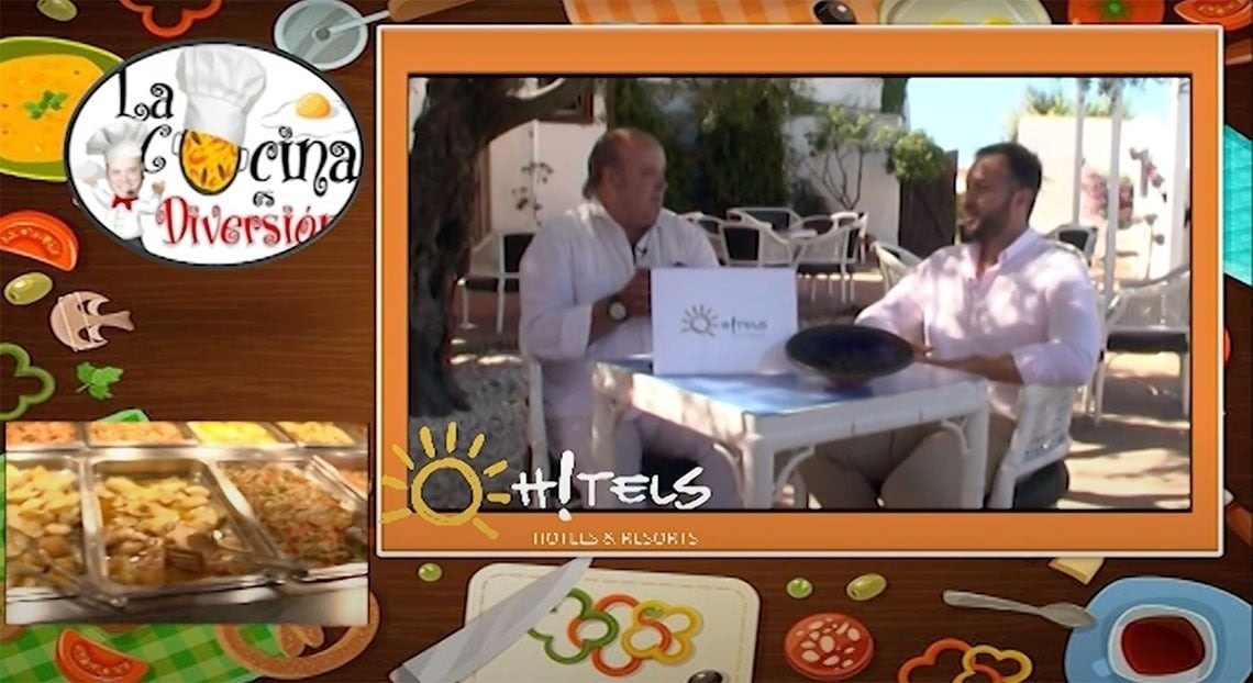 La imagen muestra la moderna entrada de cristal de un edificio con el letrero "GRAN HOTEL ALMERIA" en su fachada de azulejos grises, flanqueada por plantas en macetas.