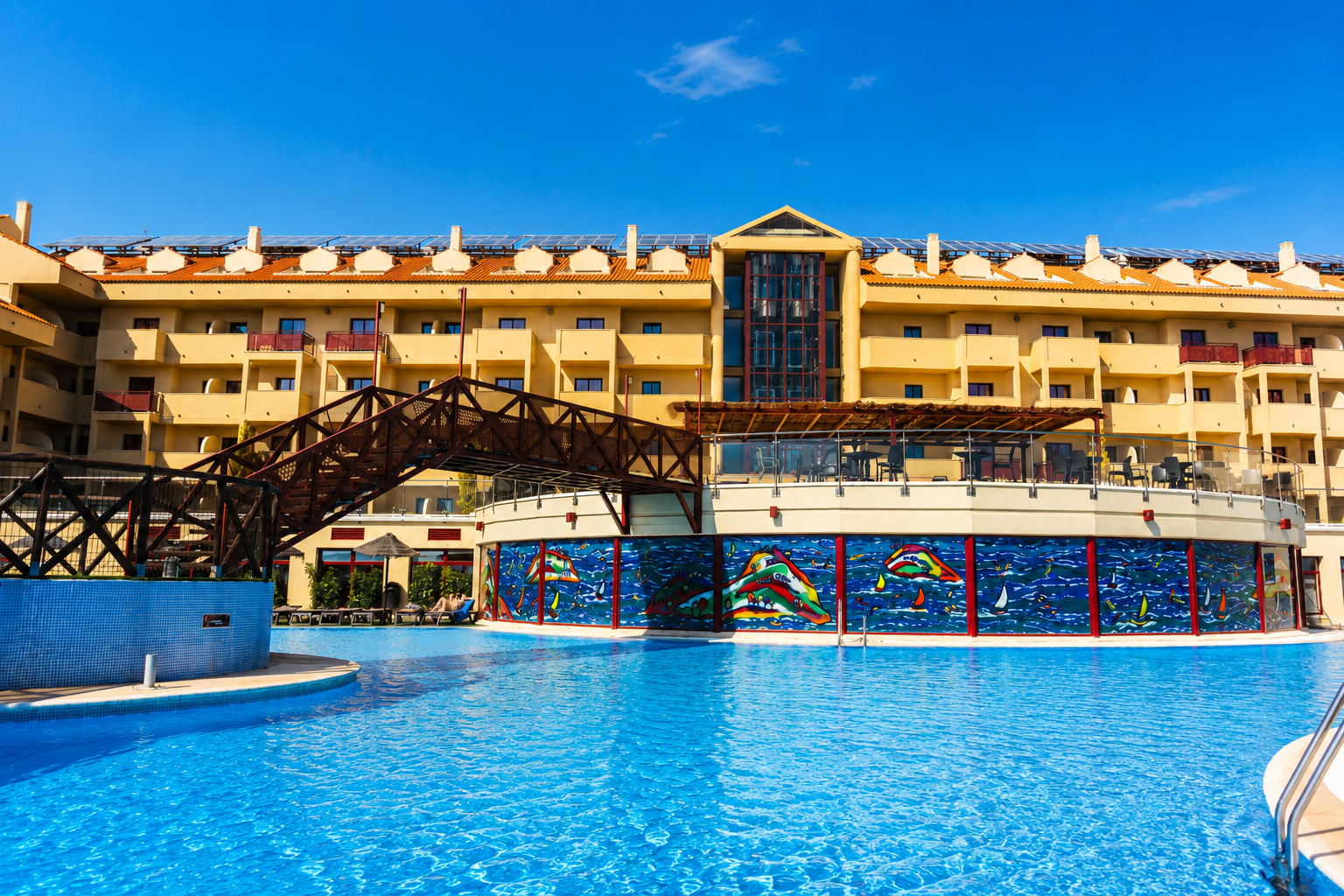 Resort pool with colorful mural and building in background. All-inclusive hotel in Mazagón, Huelva | Ohtels Mazagon.
