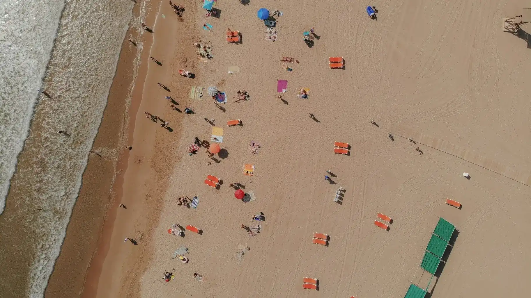 Farol branco e vermelho em praia de areia com céu degradê Hotel Campo de Gibraltar
