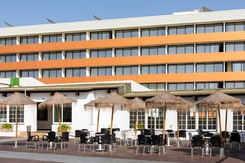 une rangée de tables et d' parasols devant un grand bâtiment