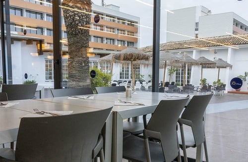 Comedor exterior del Hotel Ohtels Carabela, Matalascañas, con mesas y sillas bajo sombrillas.
