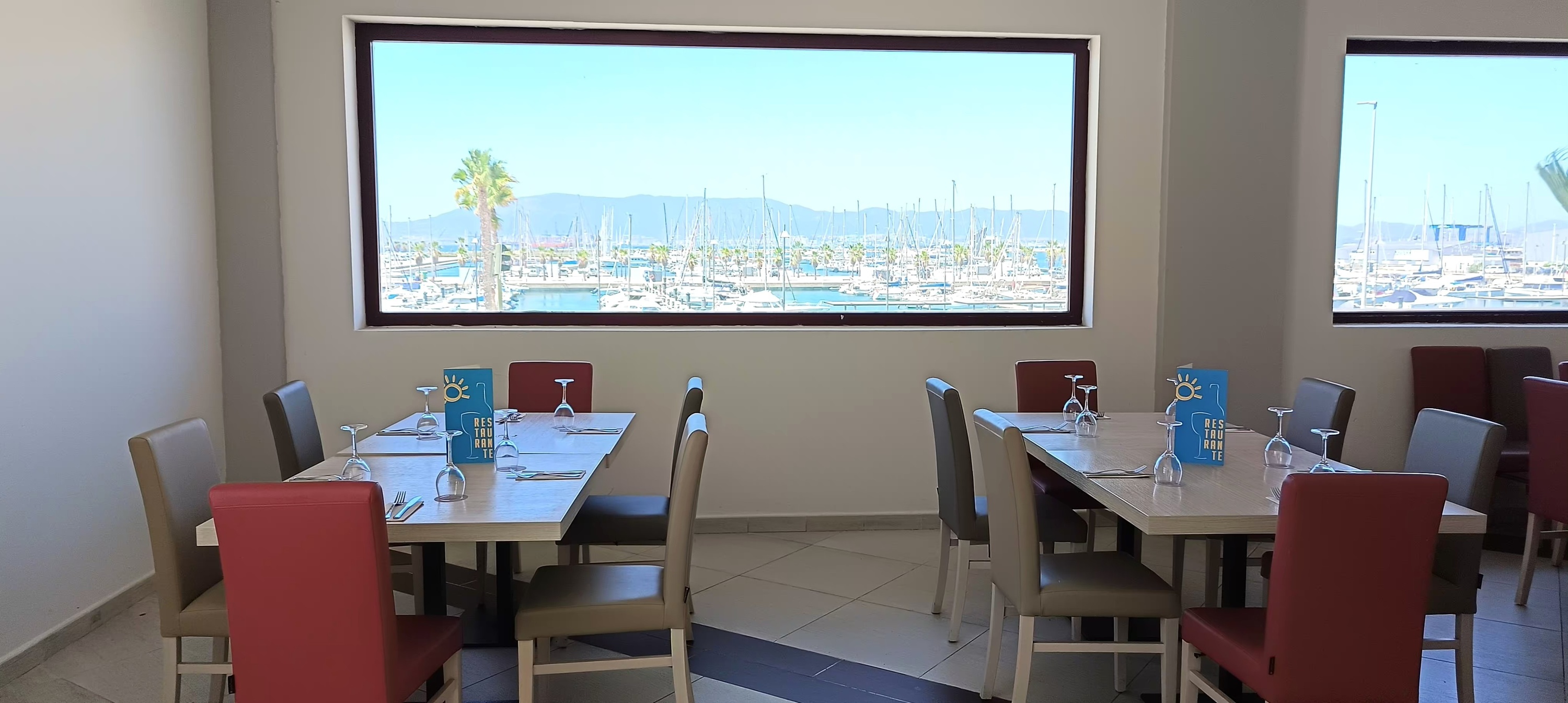 un restaurante con mesas y sillas y una ventana con vistas al puerto