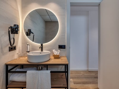 un baño con un lavabo y un espejo redondo