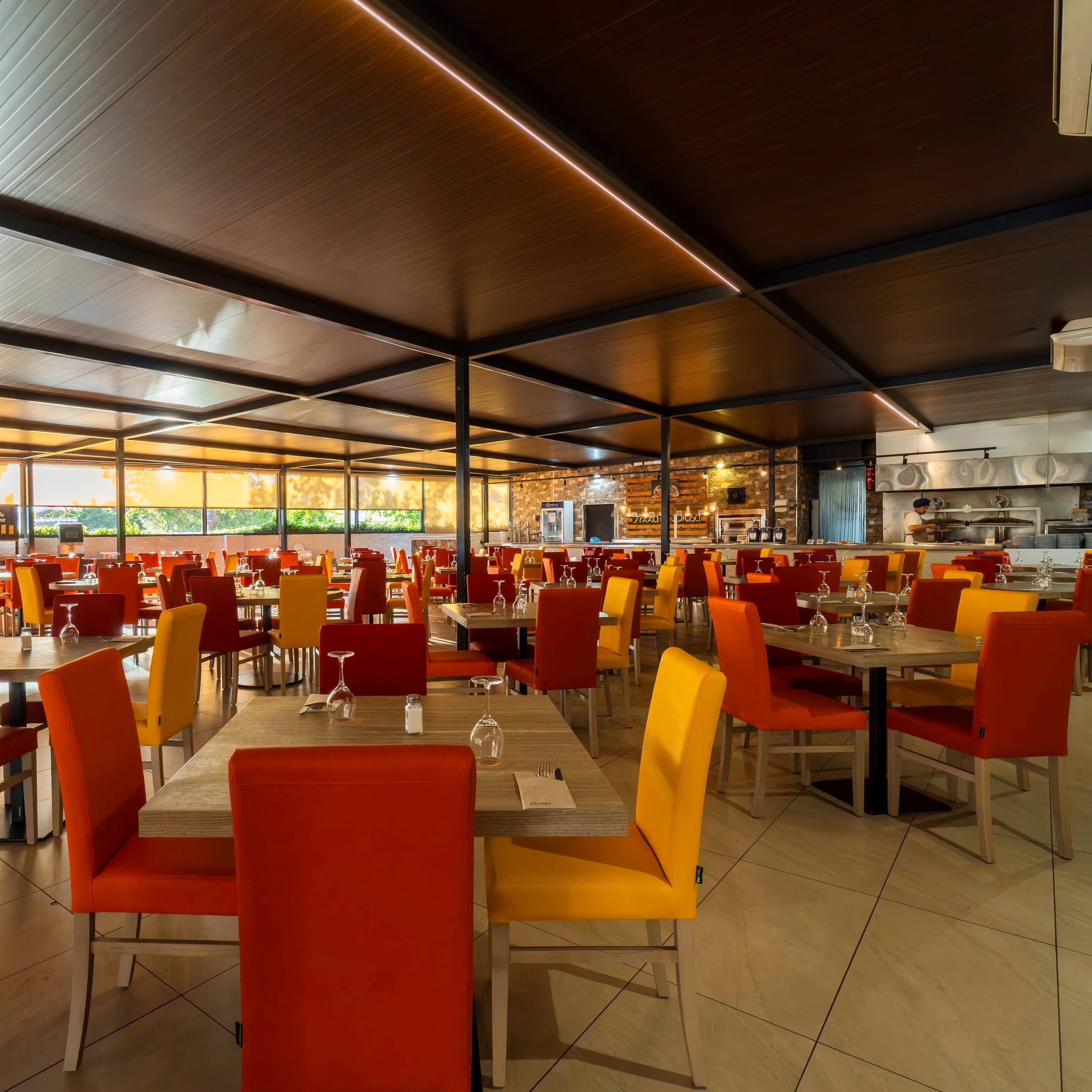 une grande salle à manger avec des tables et des chaises orange et jaune