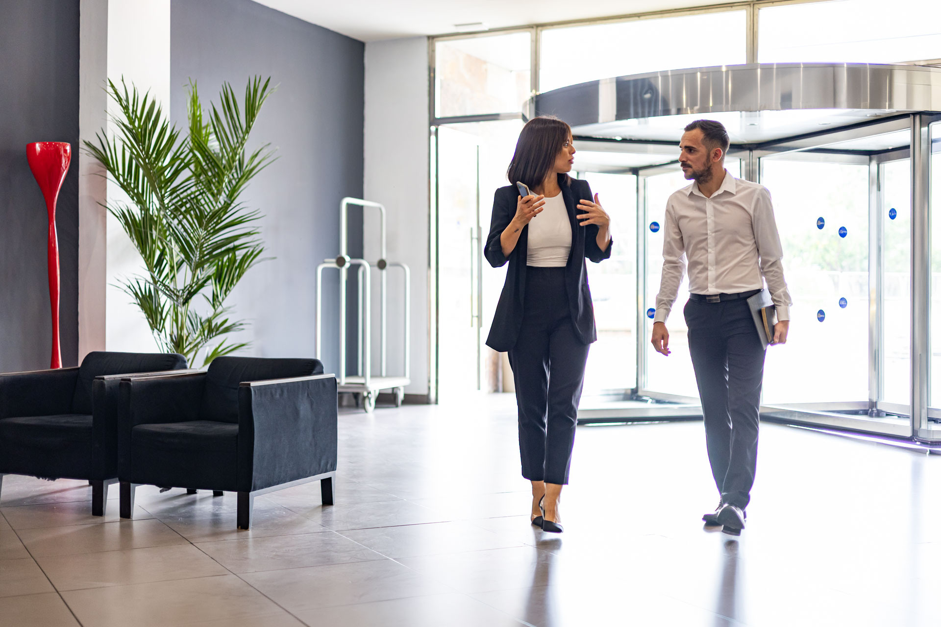 Pareja de negocios caminando en el vestíbulo de un hotel, unOhtels: Corporativa