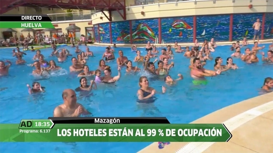 The entrance of the Gran Hotel Almeria is shown with its name prominently displayed above glass doors, flanked by potted plants and set against a light grey tiled facade.