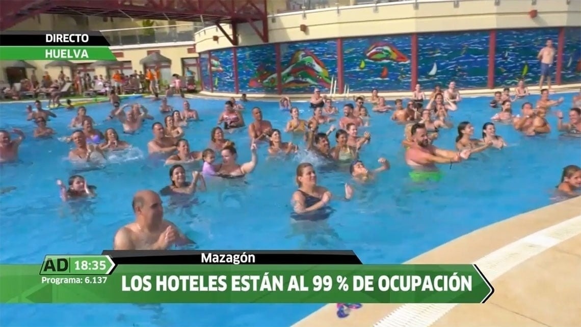 La imagen muestra la moderna entrada de cristal de un edificio con el letrero "GRAN HOTEL ALMERIA" en su fachada de azulejos grises, flanqueada por plantas en macetas.