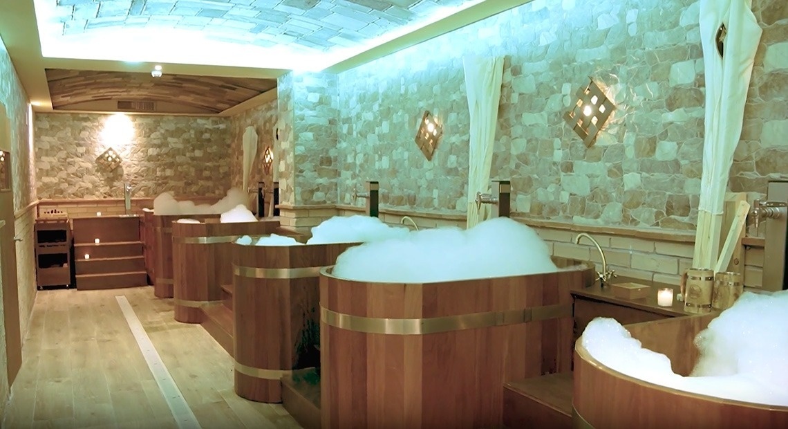 A entrada do Gran Hotel Almeria é mostrada, com portas de vidro, paredes de azulejos cinza e plantas em vasos ao lado.