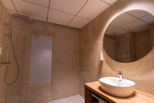 un baño con un lavabo y un espejo redondo