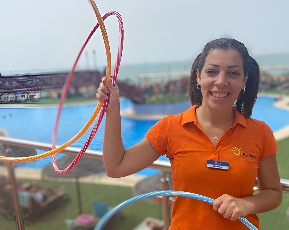 La imagen muestra la moderna entrada de cristal de un edificio con el letrero "GRAN HOTEL ALMERIA" en su fachada de azulejos grises, flanqueada por plantas en macetas.
