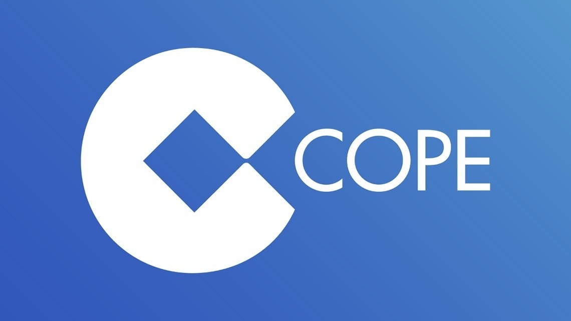 La imagen muestra la moderna entrada de cristal de un edificio con el letrero "GRAN HOTEL ALMERIA" en su fachada de azulejos grises, flanqueada por plantas en macetas.