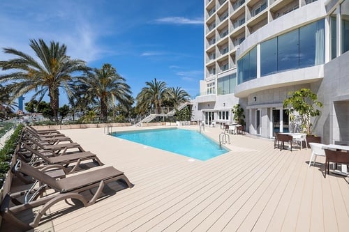 una piscina rodeada de sillas y mesas en un hotel