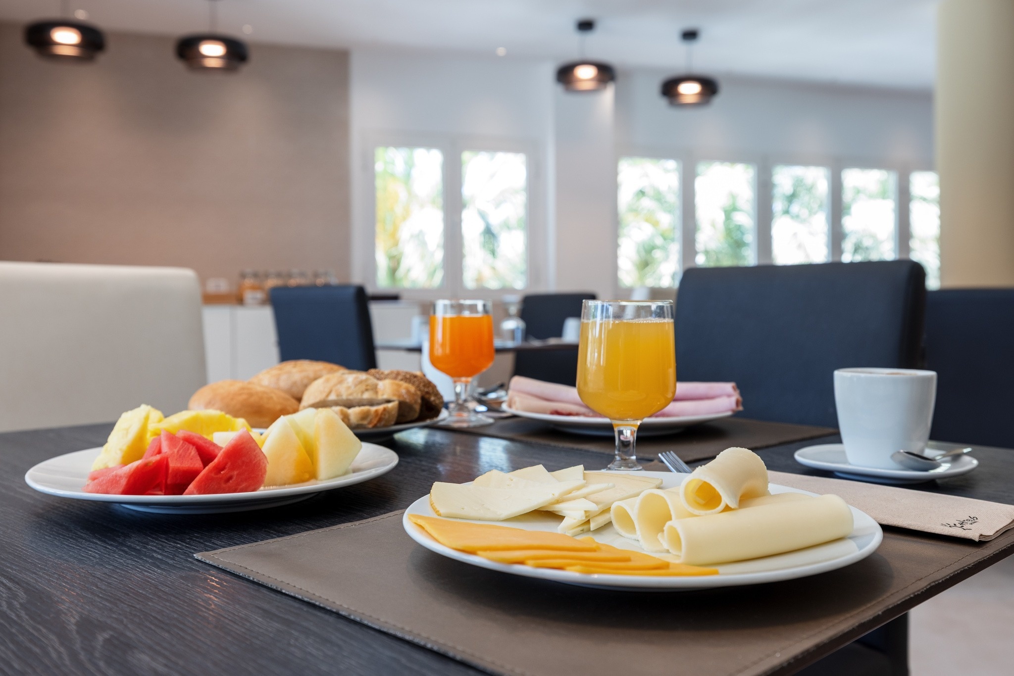 una mesa de desayuno con platos de queso y frutas