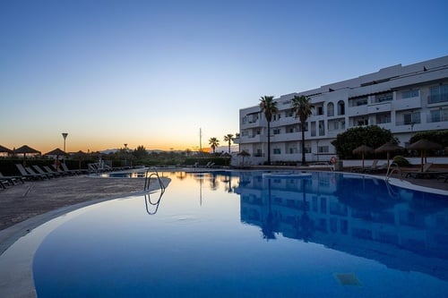 una piscina en un complejo de apartamentos al atardecer