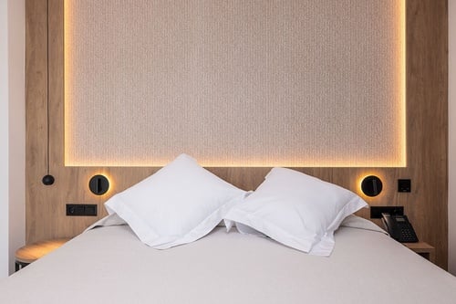 una cama con dos almohadas blancas y una pared de madera