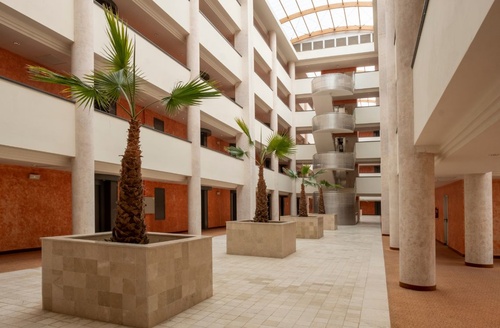 Lobby d'hôtel lumineux avec palmiers et escalier en spirale. Hôtel tout compris à Islantilla, Huelva | Ohtels Islantilla.