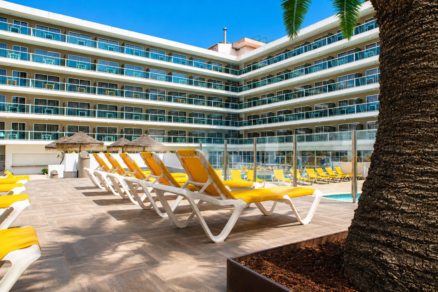Piscina exterior vibrante no centro de Salou | Ohtels Villa Dorada com espreguiçadeiras amarelas.