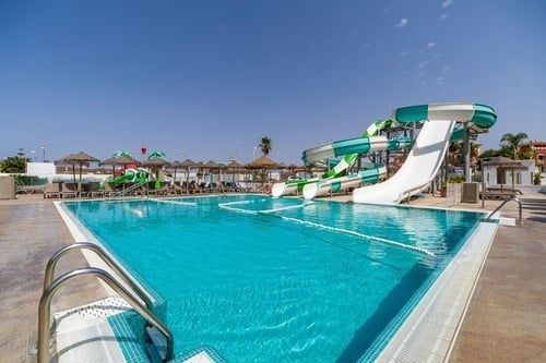 a large swimming pool with a water slide in the background