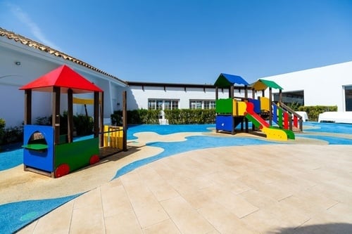 a colorful children 's playground with a white building in the background