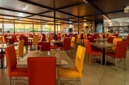 Hotel en Matalascañas: Comedor luminoso con mesas y sillas coloridas.