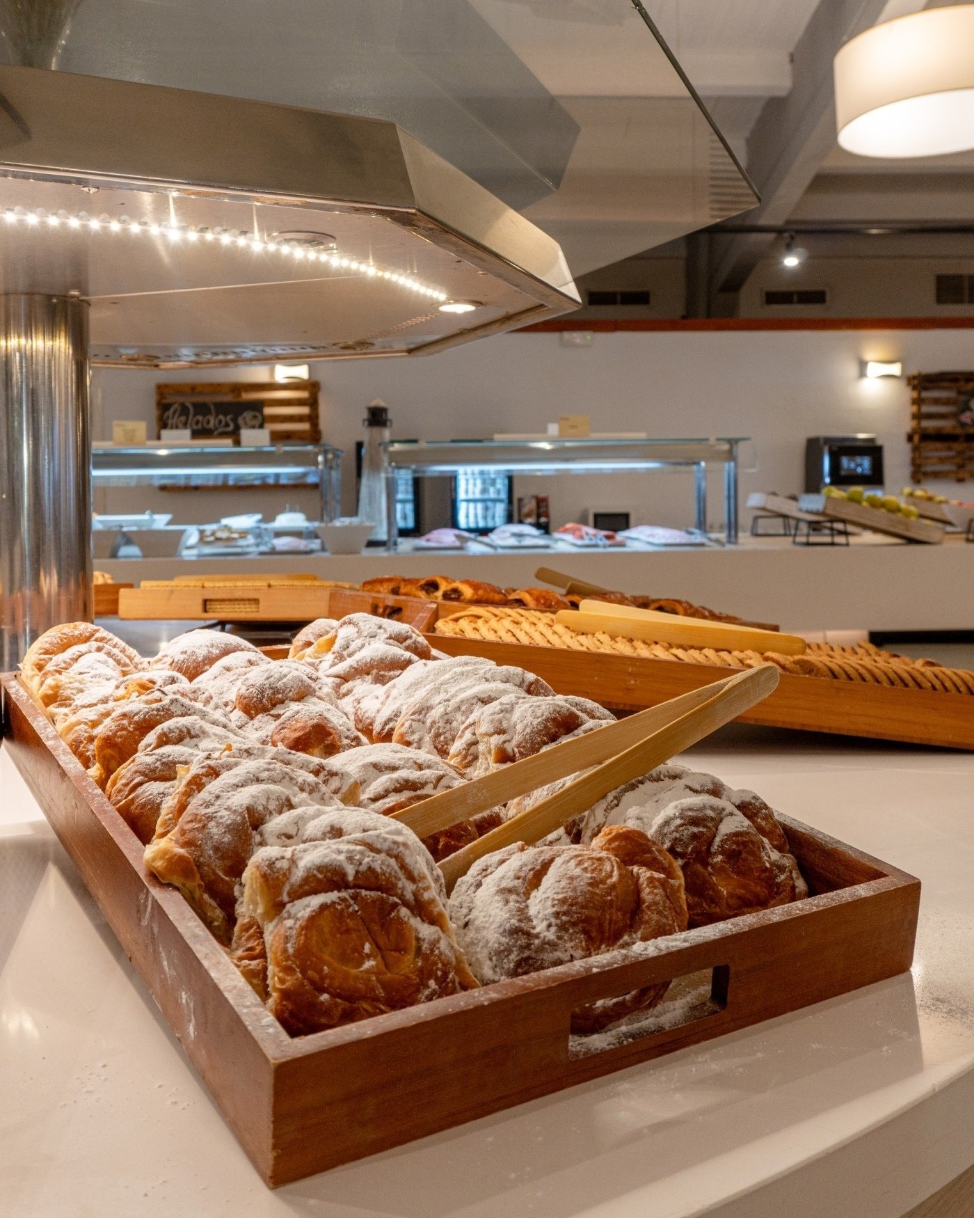 una bandeja de madera llena de croissants cubiertos de azúcar en polvo