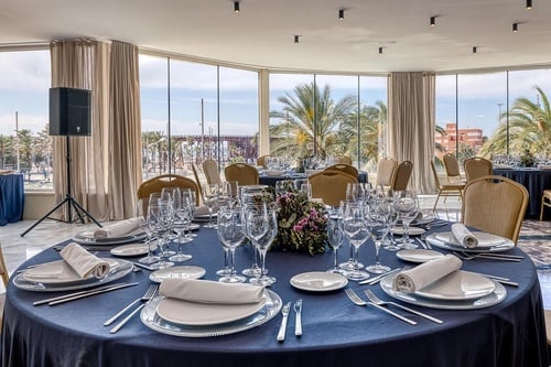 una mesa con platos y copas de vino en una habitación con muchas ventanas