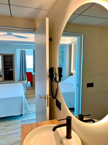 un baño con un lavabo y un espejo redondo