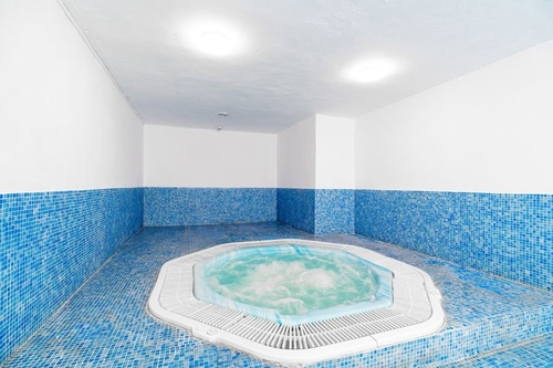 a jacuzzi in a room with blue tile walls