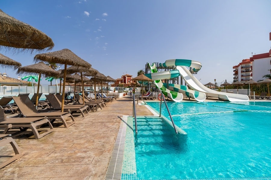 a swimming pool with chairs and umbrellas and a water slide