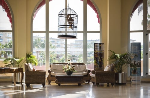 Sofá y sillones de mimbre en el lobby de un hotel todo incluido en La Pineda, Ohtels La Hacienda.