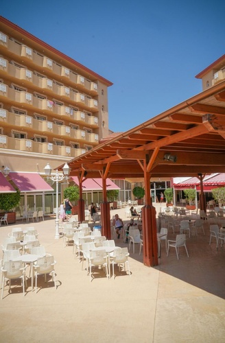 Terrasse extérieure avec tables et chaises d'un hôtel tout compris à La Pineda, Ohtels La Hacienda.