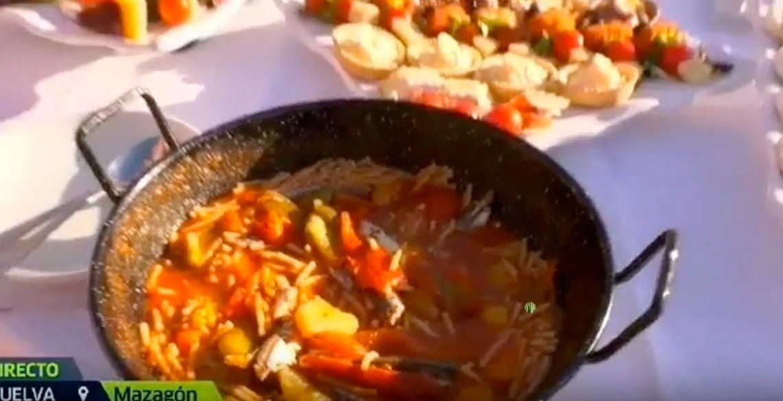 La imagen muestra la moderna entrada de cristal de un edificio con el letrero "GRAN HOTEL ALMERIA" en su fachada de azulejos grises, flanqueada por plantas en macetas.