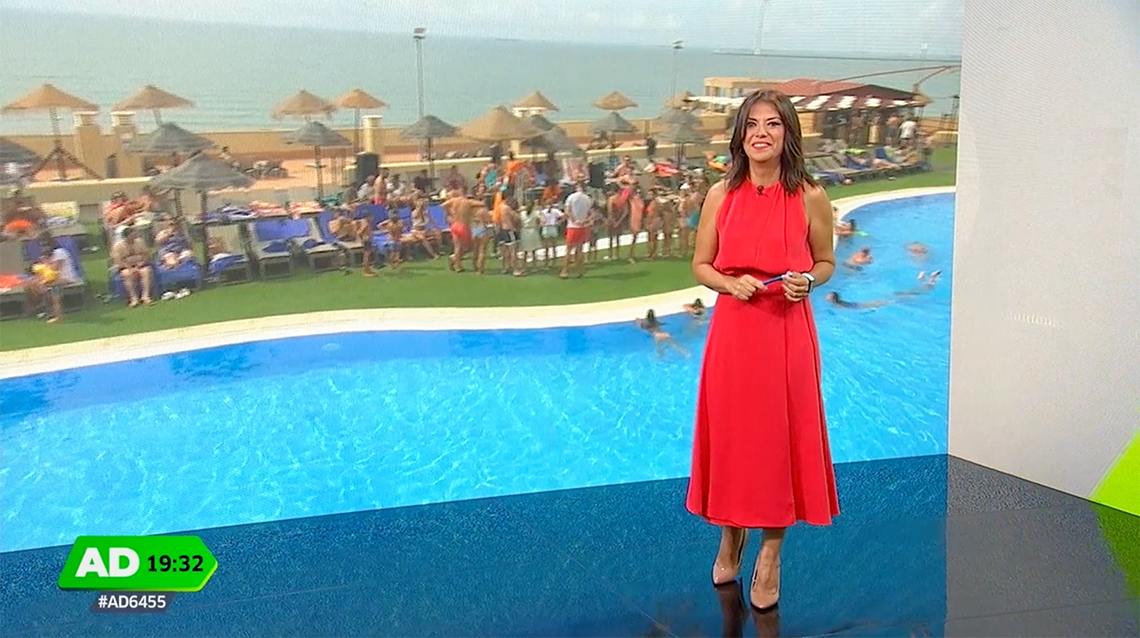 La imagen muestra la moderna entrada de cristal de un edificio con el letrero "GRAN HOTEL ALMERIA" en su fachada de azulejos grises, flanqueada por plantas en macetas.