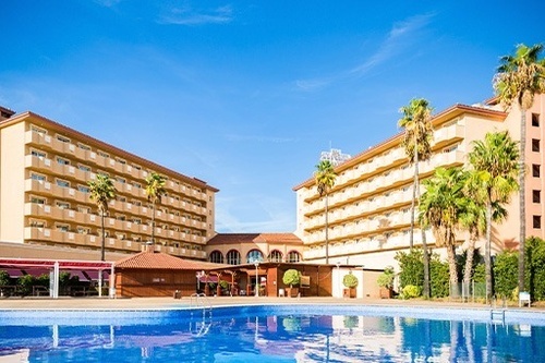 une grande piscine se trouve devant un grand bâtiment avec des palmiers .