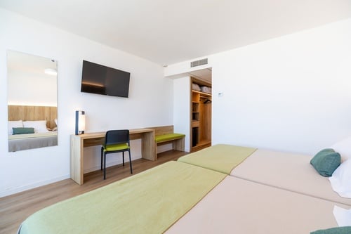 a hotel room with two beds a desk and a flat screen tv