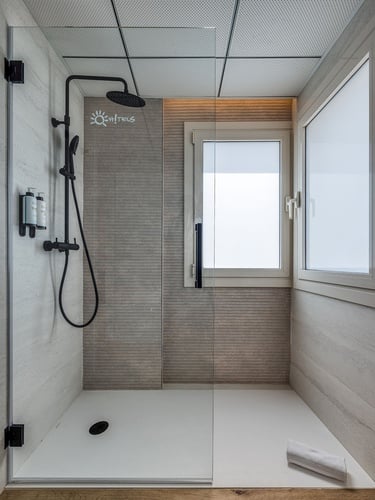 un baño con una puerta de ducha de vidrio y una ventana