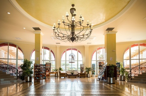 Lobby spacieuse de l'Hôtel Ohtels La Hacienda, hôtel tout compris à La Pineda, avec lustre et escalier.