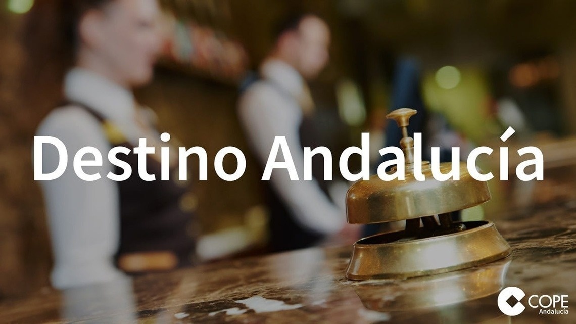 The entrance of the Gran Hotel Almeria is shown with its name prominently displayed above glass doors, flanked by potted plants and set against a light grey tiled facade.