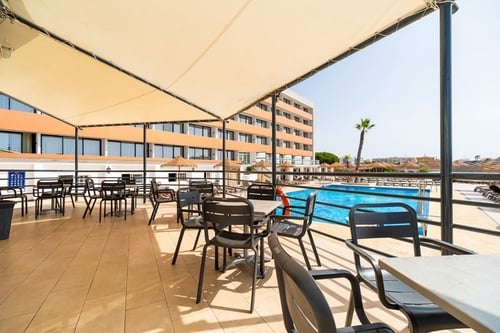 une terrasse avec des tables et des chaises à côté d' une piscine